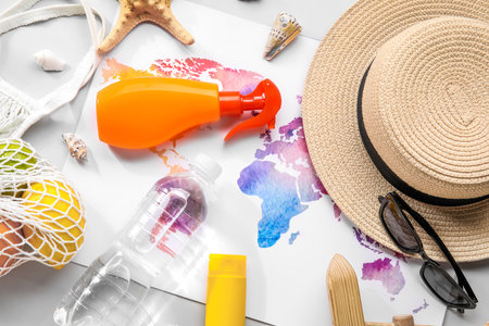 Composition with world map, sunscreen cream, bottle of water and hat on gray backgroundの写真素材
