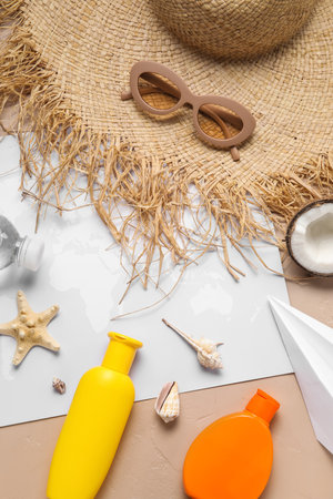 Composition with world map, bottle of sunscreen cream, paper plane, sunglasses and straw hat on brown backgroundの写真素材