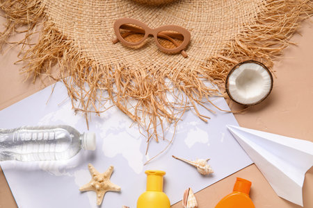 Composition with world map, bottle of sunscreen cream, paper plane, sunglasses and straw hat on...