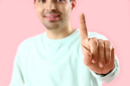 Young man using virtual screen on pink background, closeupの写真素材