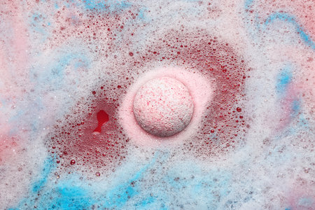 pink bath bomb dissolving in blue waterの写真素材