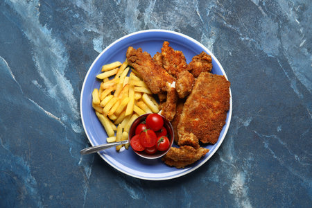Plate of tasty fried codfish with french fries on blue backgroundの写真素材