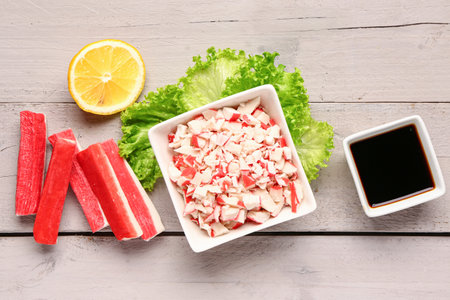 Bowl with tasty chopped crab sticks and sauce on light wooden backgroundの写真素材