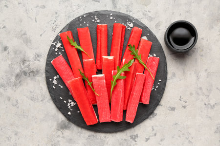 Slate board with tasty crab sticks and sauce on grunge backgroundの写真素材