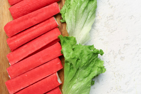 Wooden board with tasty crab sticks on light background, closeupの写真素材