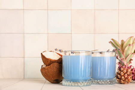 Glasses of cocktail with flowers, baby pineapples and coconut on white tile tableの写真素材