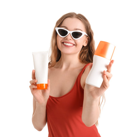 Beautiful young woman with sunscreen creams on white background