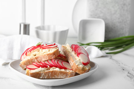 Plate with delicious radish bruschettas on white tiled tableの写真素材