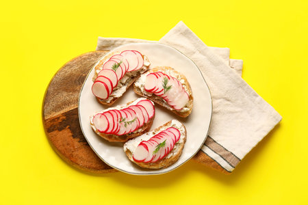 Plate with delicious radish bruschettas on yellow backgroundの写真素材