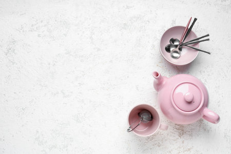 Teapot, mug and bowl with spoons on white grunge tableの写真素材