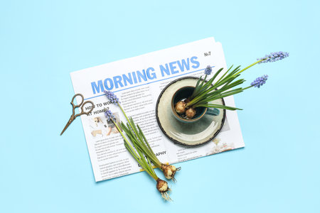 Composition with beautiful Muscari flowers, newspaper, cup and scissors on blue backgroundの写真素材