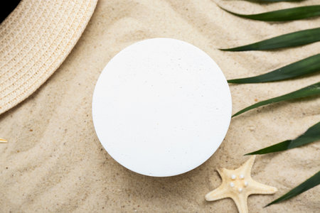 Decorative plaster podium, hat, starfish and palm leaves in sandの写真素材