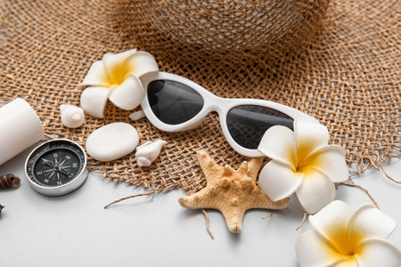 Sunglasses, compass, plumeria flowers and straw hat on gray backgroundの写真素材