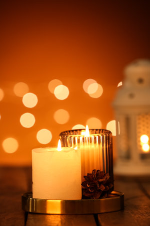 Burning candles on wooden table against blurred lightsの写真素材