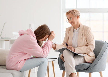 Mature psychologist working with crying patient in officeの写真素材