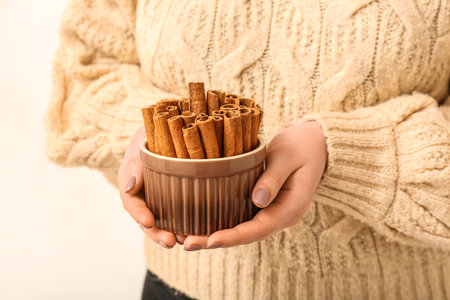 Woman holding bowl of cinnamon sticks on white background, closeupの写真素材