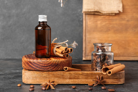 Wooden board with bottle of cosmetic product, cinnamon sticks and anise stars on dark backgroundの写真素材
