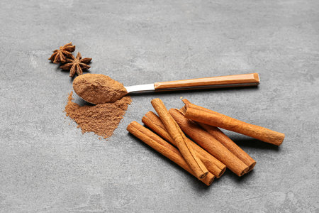 Spoon of cinnamon powder, sticks and anise stars on dark backgroundの写真素材