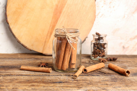 Glass jars of cinnamon sticks and anise stars on wooden table
