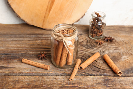 Glass jars of cinnamon sticks and anise stars on wooden tableの写真素材