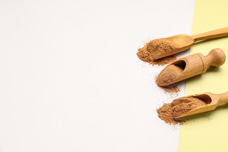 Wooden scoops with cinnamon powder on light backgroundの写真素材
