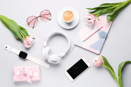 Composition with modern gadgets, gift, cup of coffee and tulip flowers on light backgroundの写真素材