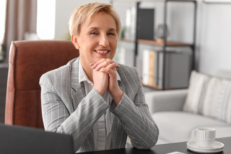 Happy mature businesswoman at workplace in officeの写真素材