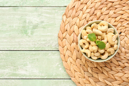 Bowl with tasty cashew nuts on light wooden backgroundの写真素材
