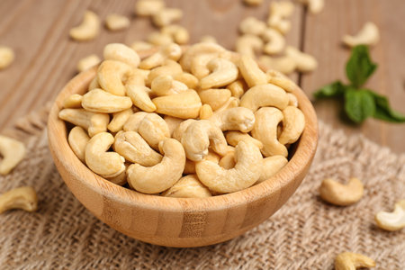 Bowl with tasty cashew nuts on wooden backgroundの写真素材