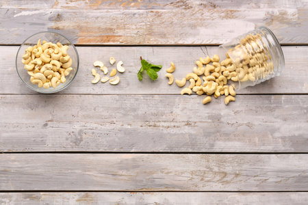 Bowl and jar with tasty cashew nuts on light wooden backgroundの写真素材