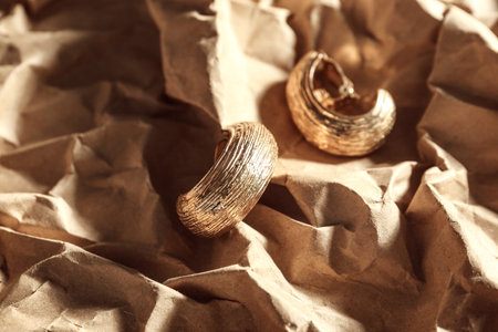 Golden earrings on crumpled paper, closeupの写真素材