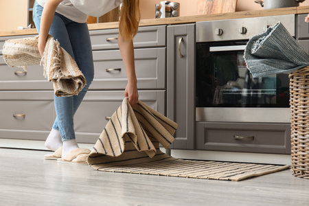 Woman placing rug on floor in modern kitchenの写真素材