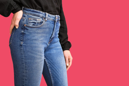 Young woman in stylish jeans on red background, closeup