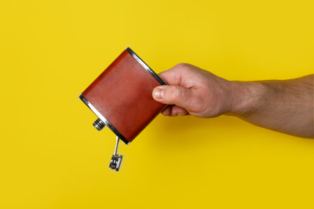 Man holding hip flask on yellow backgroundの写真素材