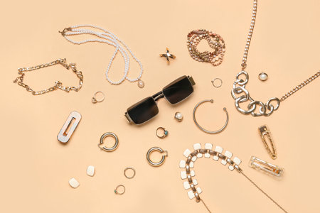 Stylish jewelry with sunglasses on beige backgroundの写真素材
