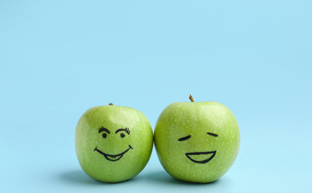 Apples with happy faces on blue background. friendship day celebrationの写真素材