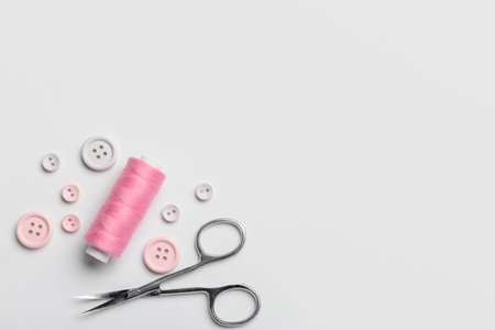 Composition with thread spool, scissors and buttons on light backgroundの写真素材