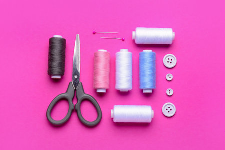Composition with thread spools and sewing supplies on pink backgroundの写真素材