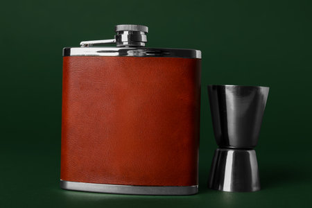 New hip flask and measure cup on green backgroundの写真素材