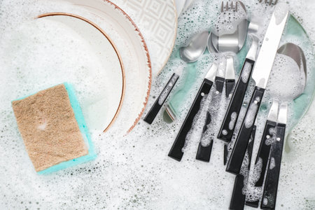 Cleaning sponge with dishes and foam in water, closeupの写真素材