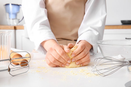 Woman kneading dough for Italian Grissini at white table in kitchenの写真素材