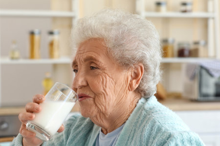 Senior woman drinking milk in kitchen, closeupの写真素材