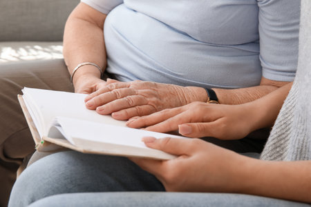 Senior woman with her granddaughter reading book at home, closeupの写真素材