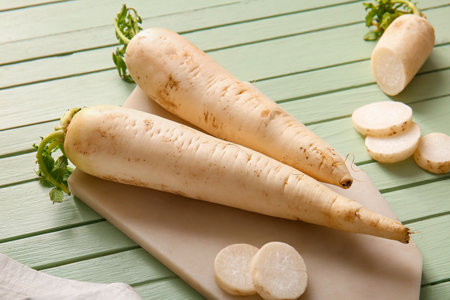 Board with fresh daikon radishes on green wooden backgroundの写真素材