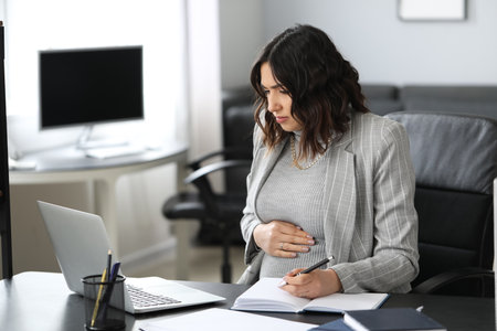 Young pregnant woman working at table in officeの写真素材