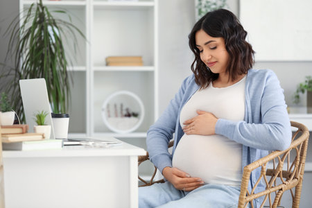 Young pregnant woman working at table in officeの写真素材