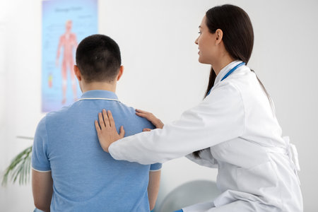Female doctor checking posture of young man in clinicの写真素材