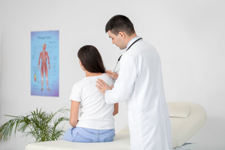 Male doctor checking posture of young woman in clinicの写真素材