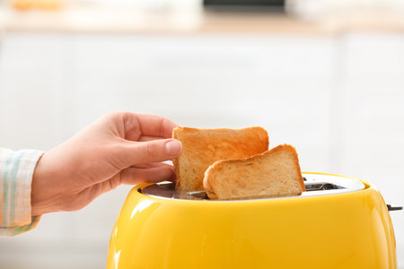 Woman taking crispy bread slice from modern toaster, closeupの写真素材