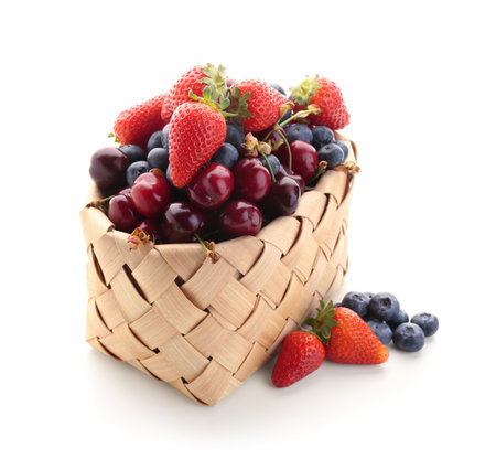 Wicker basket with different ripe berries on white backgroundの写真素材